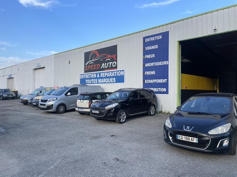 Le bâtiment de Speed Auto 26 dans la ZA du Morlon : bardage gris clair, enseigne Speed Auto, panneaux bleus « Entretien et réparation toutes marques »
